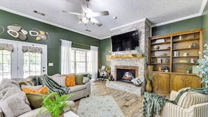 A living room with a fireplace, a sofa, a coffee table, and a bookshelf. - Game Day Hideaway! Spacious Opelika Escape (Opelika)