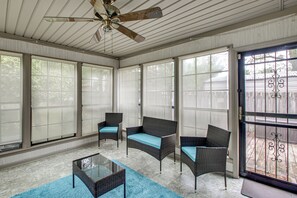 A sunroom with large windows, wicker furniture, and a ceiling fan. - Sun Porch w/ Fireplace! Family Home By Little Rock (Alexander)