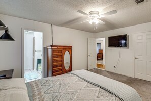 A bedroom with a bed, a dresser, a ceiling fan, a television, and a door. - Sun Porch w/ Fireplace! Family Home By Little Rock (Alexander)