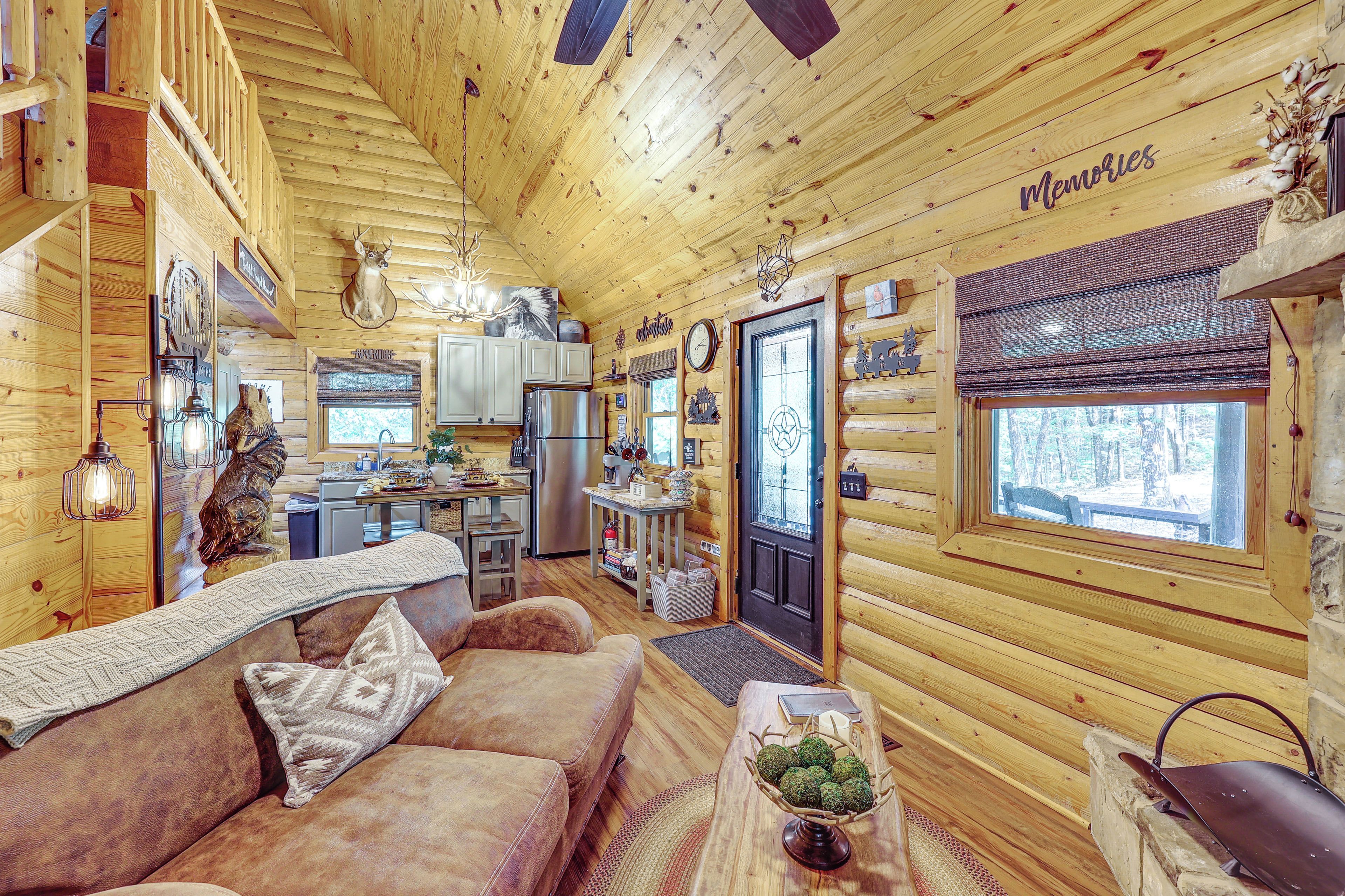 A log cabin interior with a cozy living area, kitchen, and a dining space.