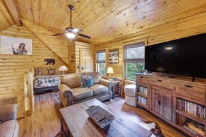 Un interior de cabaña acogedor con un sofá, un televisor y una estantería.