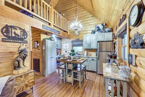 A cabin interior with a wooden interior, a dining area, kitchen, and a loft space. - 'wolf Ridge Lodge' w/ Hot Tub & Fire Pit! (Mena)