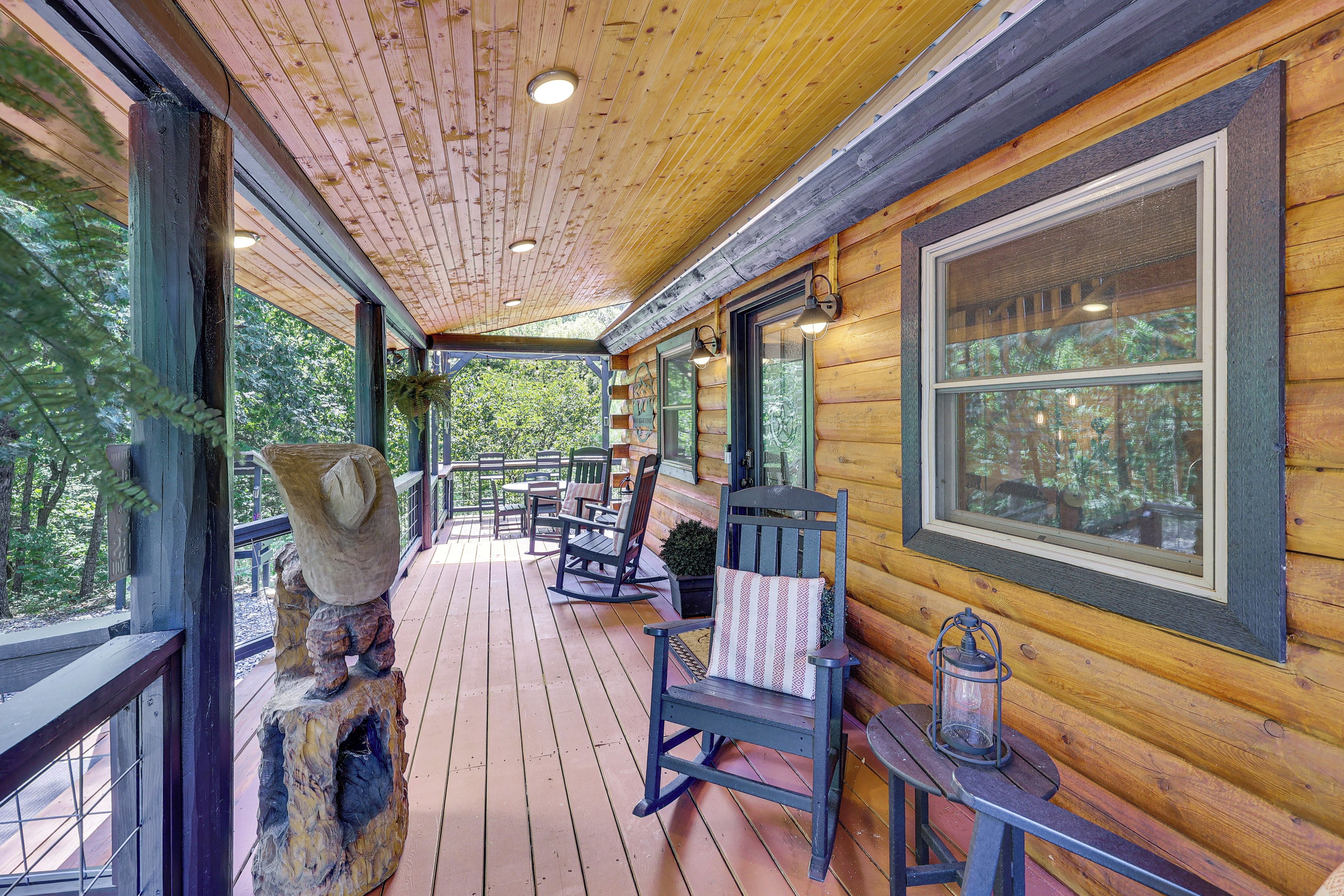 A wooden cabin with a covered porch, rocking chairs, and a lantern.