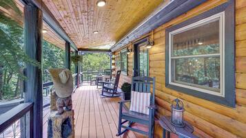 A wooden cabin with a covered porch, rocking chairs, and a lantern.