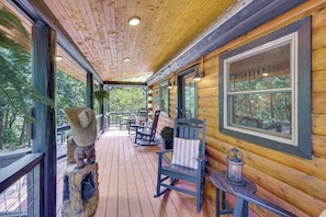 A wooden cabin with a covered porch, rocking chairs, and a lantern. - 'wolf Ridge Lodge' w/ Hot Tub & Fire Pit! (Mena)