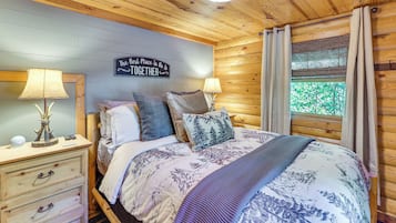 A cozy bedroom with a bed, two bedside tables, a wall clock, and a sign that reads 'The Best Place To Be Is Together.'