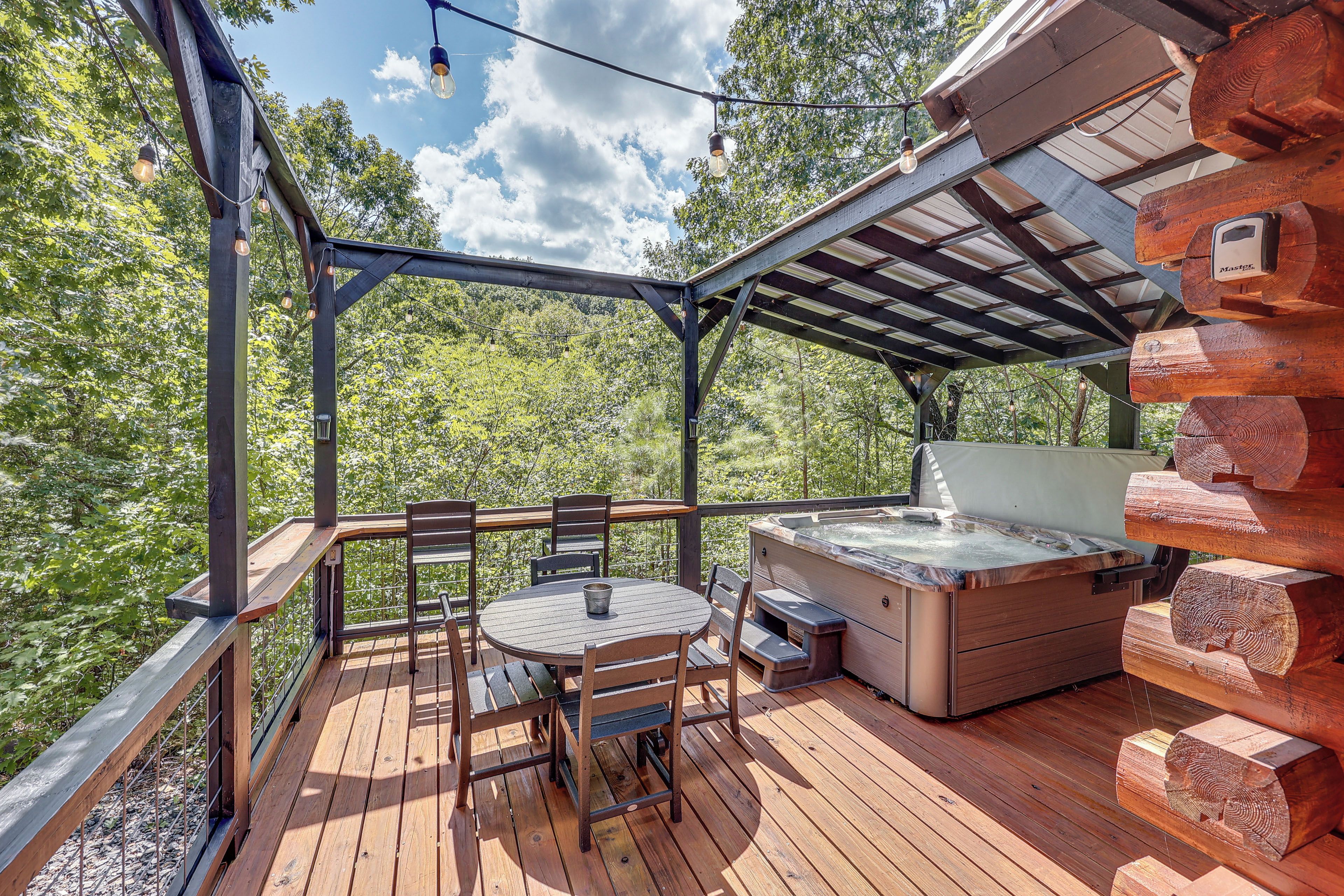 A wooden deck with a hot tub, outdoor seating, and a pergola.