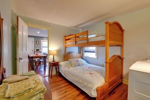 Una habitación con literas, un escritorio con silla, una lámpara y una cama con colcha.