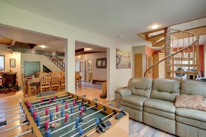 A spacious living area with a foosball table, a leather sofa, and a wooden staircase. - Near Heavenly & Lake Tahoe! Mountain Home, Hot Tub (South Lake Tahoe)