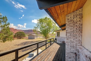 A wooden deck with a brick wall, a fenced area, and a view of a mountainous landscape. - Red Rock Retreat in Kanab Epic Views Near Zion (Kanab)