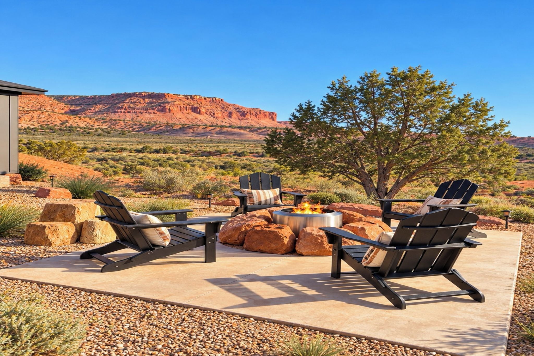 An outdoor seating area with Adirondack chairs and a fire pit, set against a desert landscape with mountains in the background.