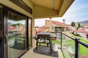 A balcony with a grill, a gas cylinder, and a view of neighboring houses.