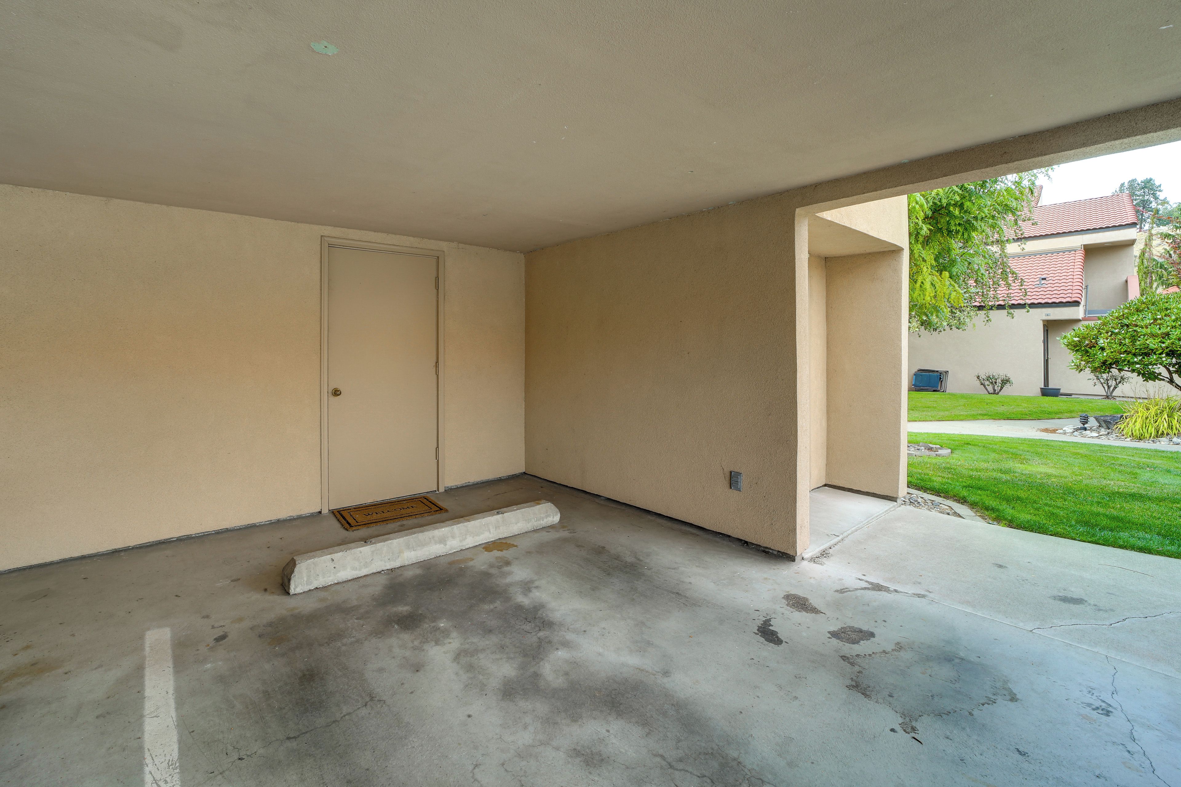 A room with a door, a small step leading to the entrance, and a concrete floor.