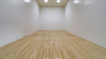 A squash court with wooden flooring and red boundary lines.