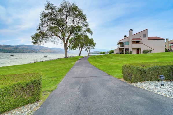 A pathway leading to a building with a view of a lake and mountains.