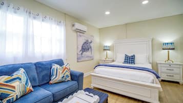 Une chambre à coucher avec un lit, une table de chevet, une lampe, un canapé et une fenêtre avec des rideaux.