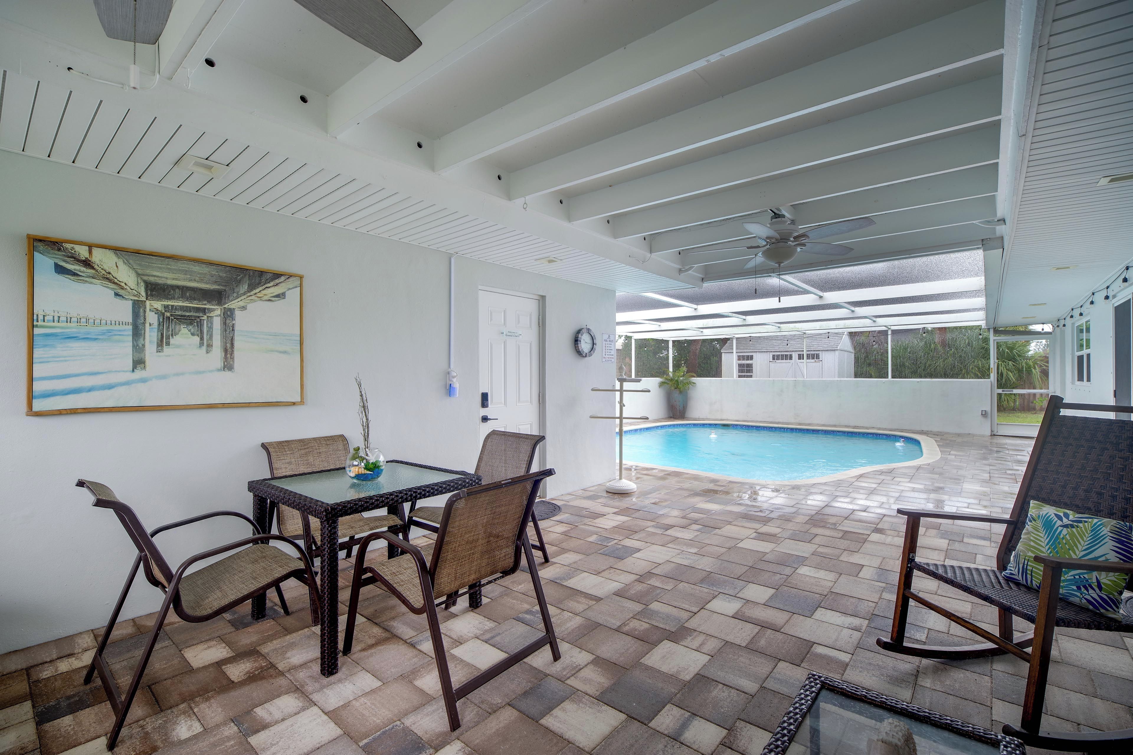Un patio techado con piscina, mobiliario exterior y un cuadro en la pared.