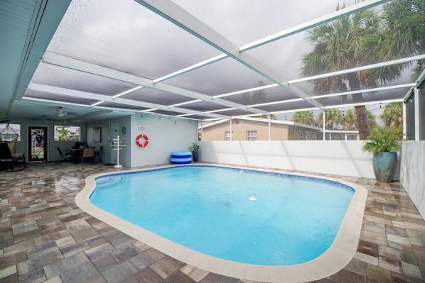 An indoor swimming pool with a tiled floor, a ceiling with glass panels, and a lifebuoy on the wall.