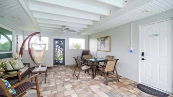 A room with a dining table, chairs, a hammock, and a door with a welcome sign.