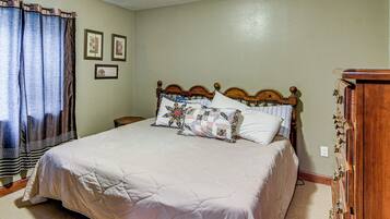 A bedroom with a large bed, a wooden headboard, a nightstand, and a dresser.