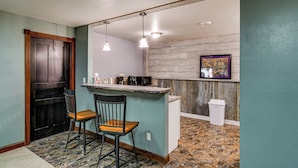 A kitchen with a bar area, two chairs, a trash can, and a framed picture on the wall. - 9 Mi to Clear Lake! Cozy Apartment (Garner)