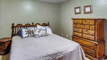 A bedroom with a wooden bed, a dresser, and two framed certificates on the wall.