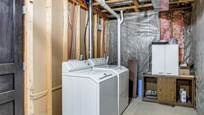 A laundry room with a washing machine and dryer, wooden cabinets, and exposed ductwork. - 9 Mi to Clear Lake! Cozy Apartment (Garner)