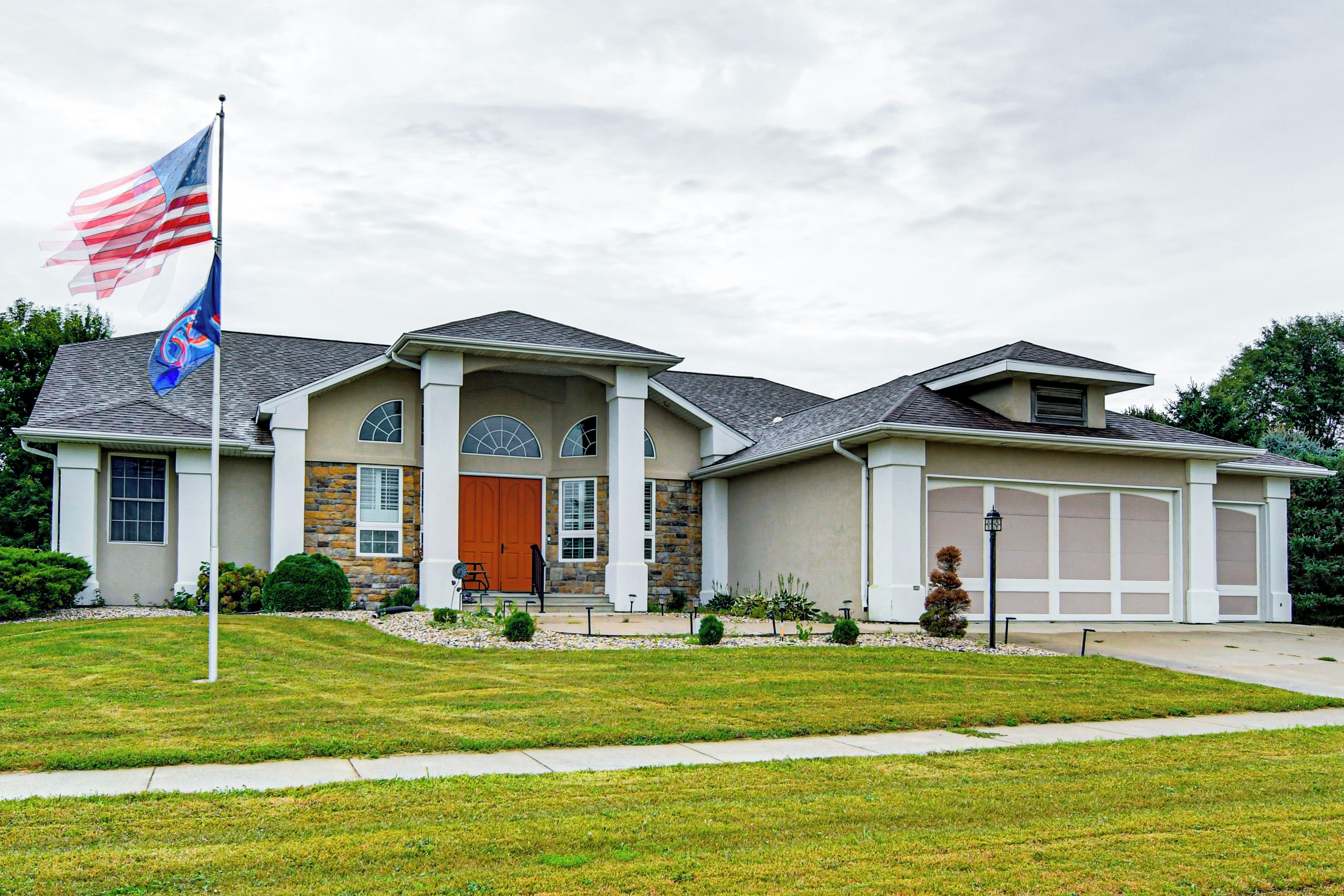 A two-story house with a stone facade, a large garage, and a well-maintained lawn.