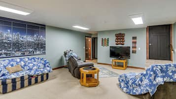 A living room with a cityscape view, a reclining chair, a flat-screen TV, and a wooden coffee table.