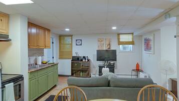 A living room with a sofa, a dining table, and a kitchen area with cabinets and appliances.