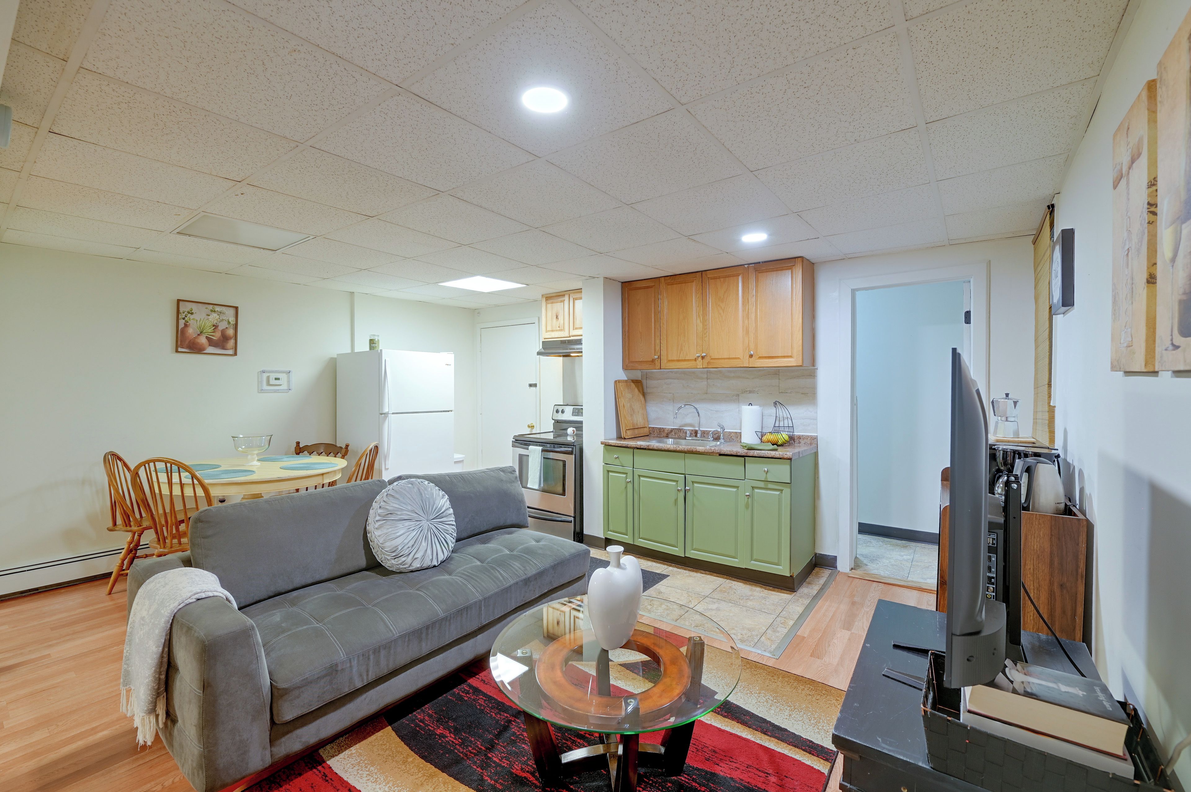 A compact living space with a sofa, dining table, kitchenette, and a television.