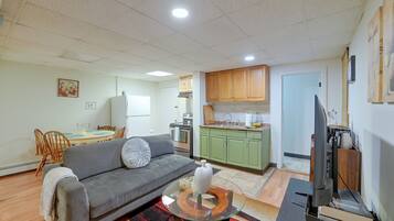 A compact living space with a sofa, dining table, kitchenette, and a television.