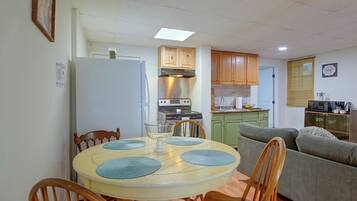 A compact kitchen with a dining area, wooden cabinets, and a microwave.