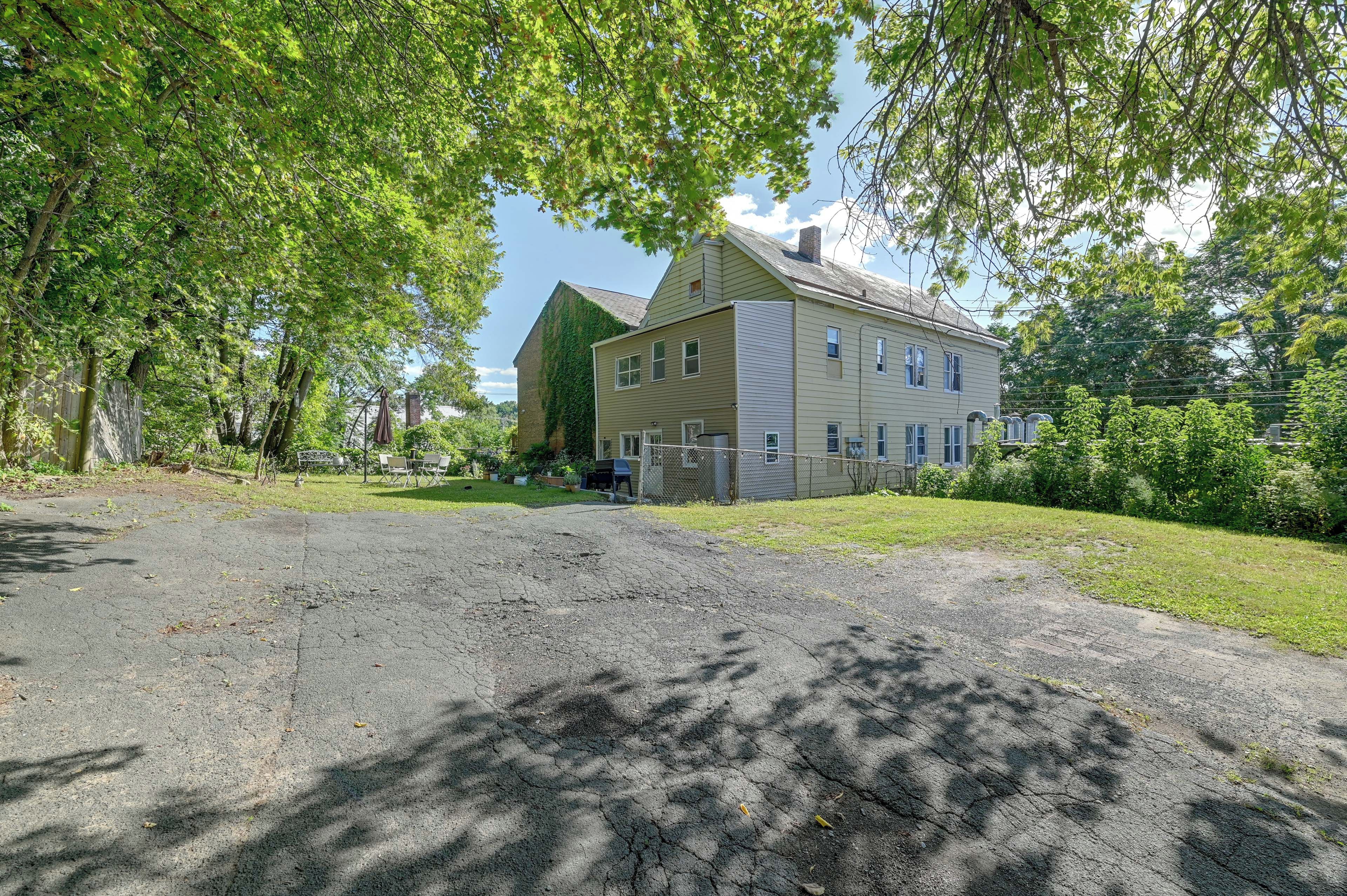 A two-story house with a fenced yard and a gravel driveway.