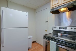A compact kitchen with a white refrigerator, a stainless steel stove, and a white toilet.