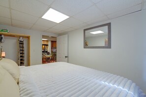 Un dormitorio con cama, espejo y una kitchenette al fondo.