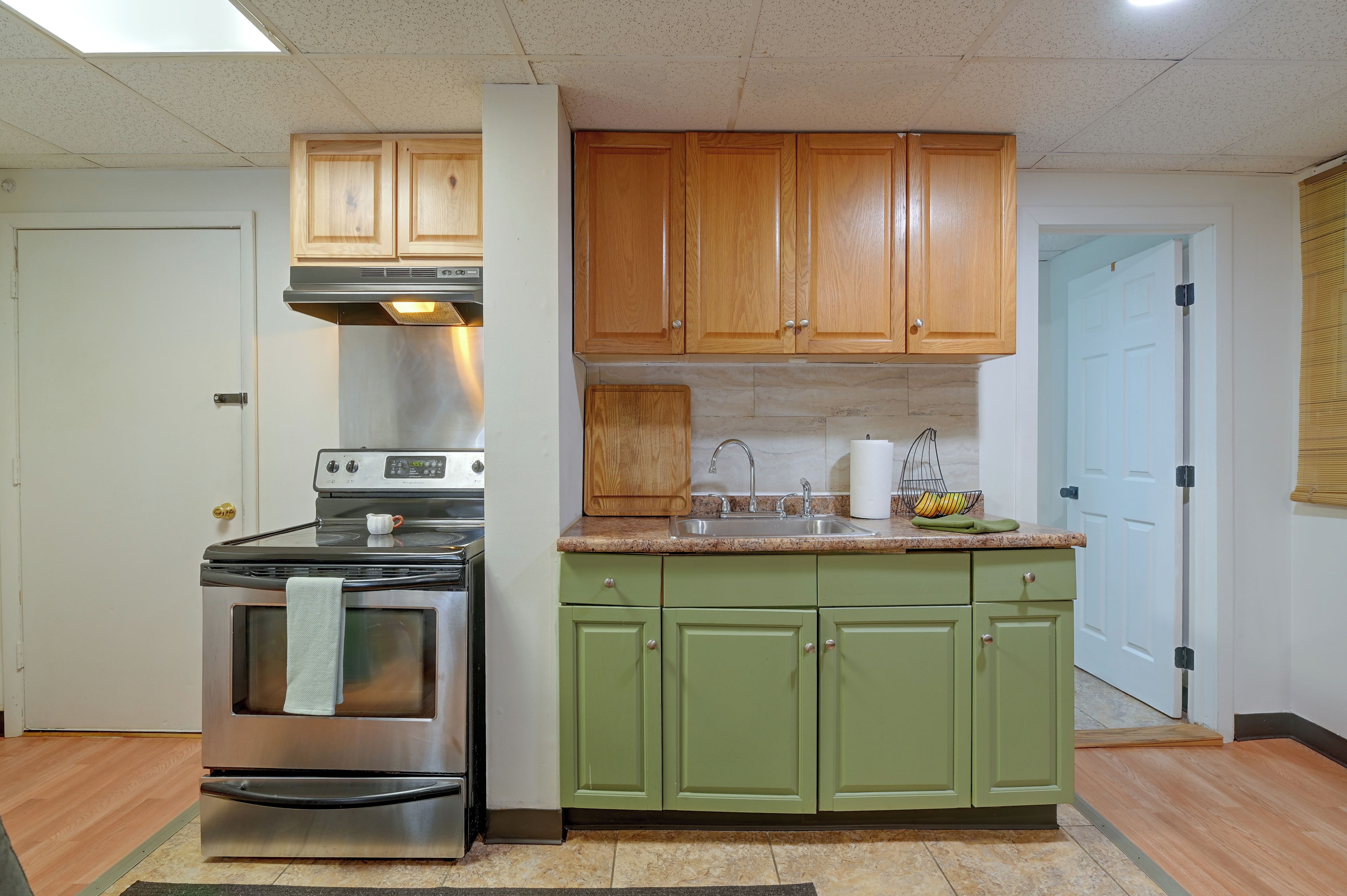 A kitchen with a stainless steel stove, wooden cabinets, a granite countertop, and a green sink.