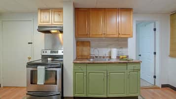 A kitchen with a stainless steel stove, wooden cabinets, a granite countertop, and a green sink.