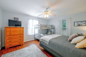 Ein Schlafzimmer mit Etagenbett, Kommode, Deckenventilator und Fernseher.