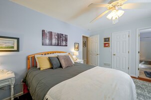 Un dormitorio con cama, ventilador de techo, mesita de noche y una puerta.