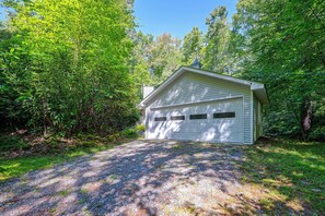 A single-story building with a garage, surrounded by dense green foliage. - Ski & Hike! Cozy Sapphire Retreat (Sapphire)