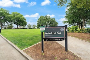 A sign for Waterfront Park with a grassy area and trees in the background. - Walkable Old Town Retreat Near the Waterfront (Alexandria)