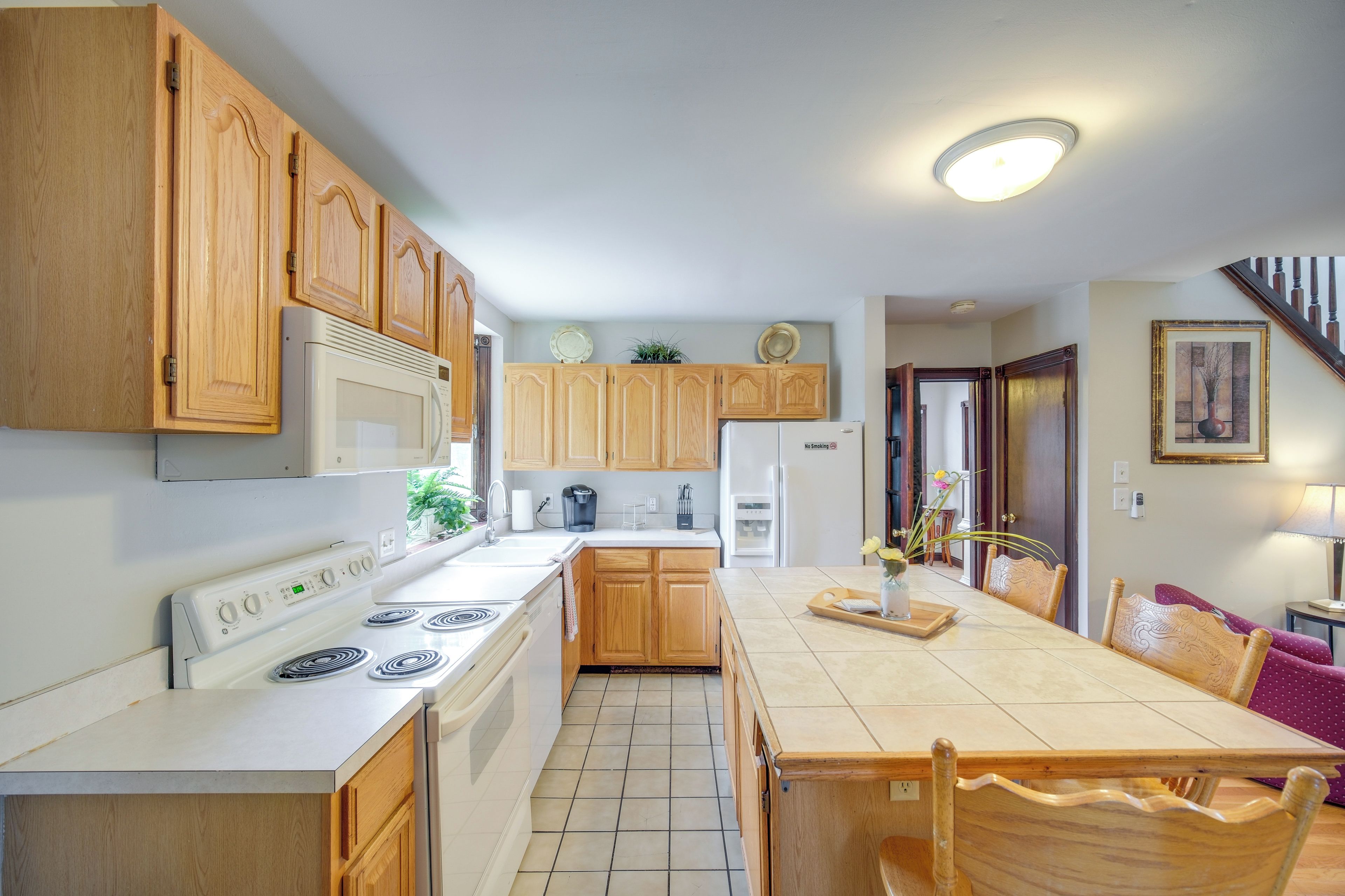 Une cuisine avec des meubles de rangement en bois, une cuisinière, un réfrigérateur et une table à manger avec des chaises.