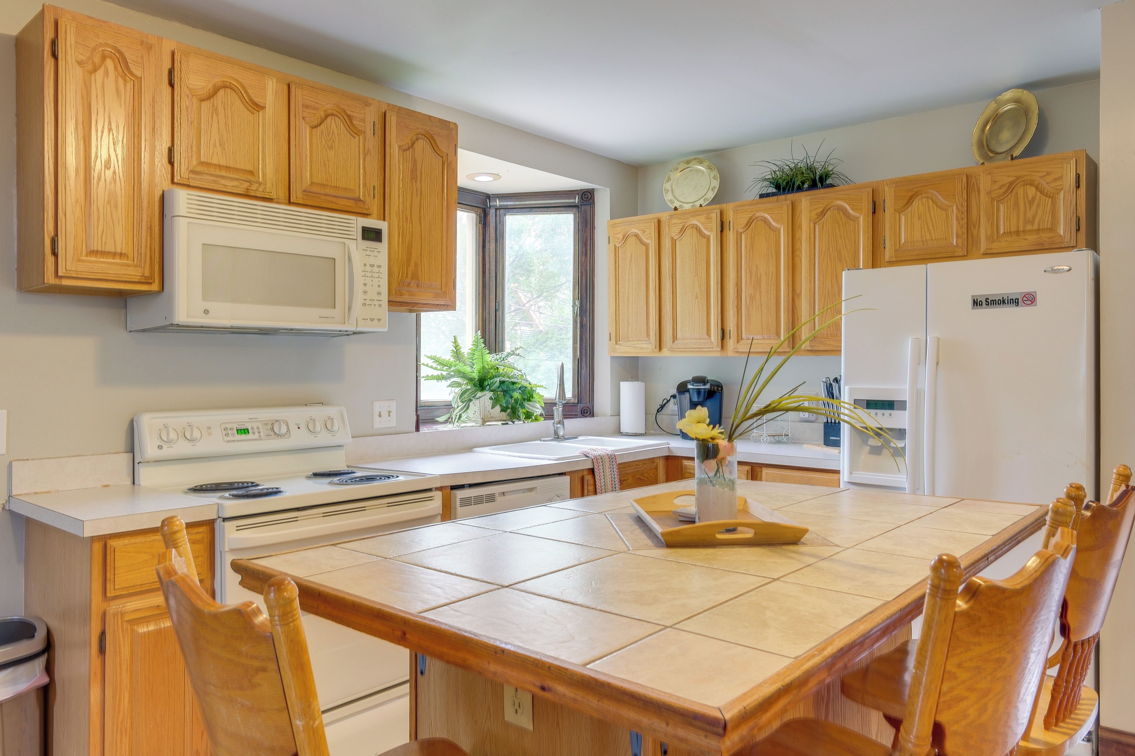 Une cuisine avec des meubles de rangement en bois, un four à micro-ondes, une cuisinière, un réfrigérateur et une table à manger avec des chaises.