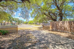 A residential street with a sidewalk, wooden fences, and trees. - Little Minnow - Just Minutes From the Water (Aransas Pass)