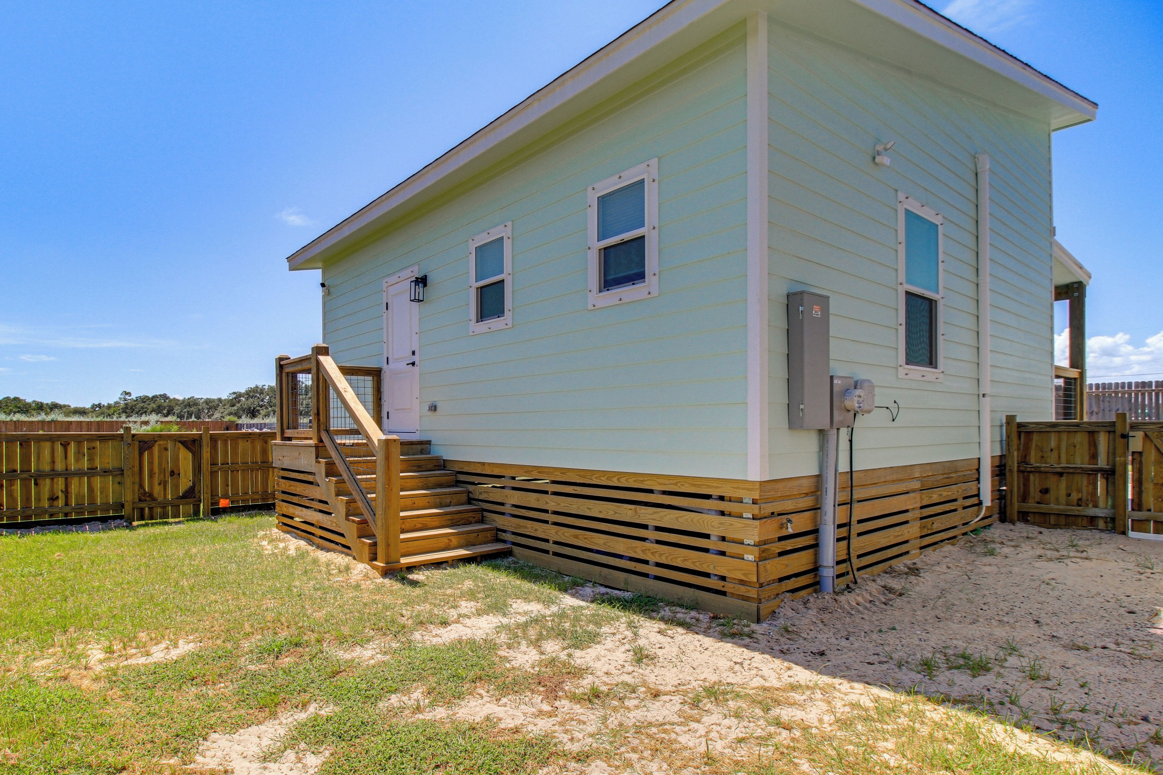 A two-story house with a wooden deck and a small staircase leading to the front door.