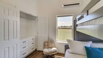 A bedroom with a bed, a chair, a wardrobe, and a window with a view.