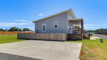 A single-story house with a front porch, a small deck, and a concrete driveway.