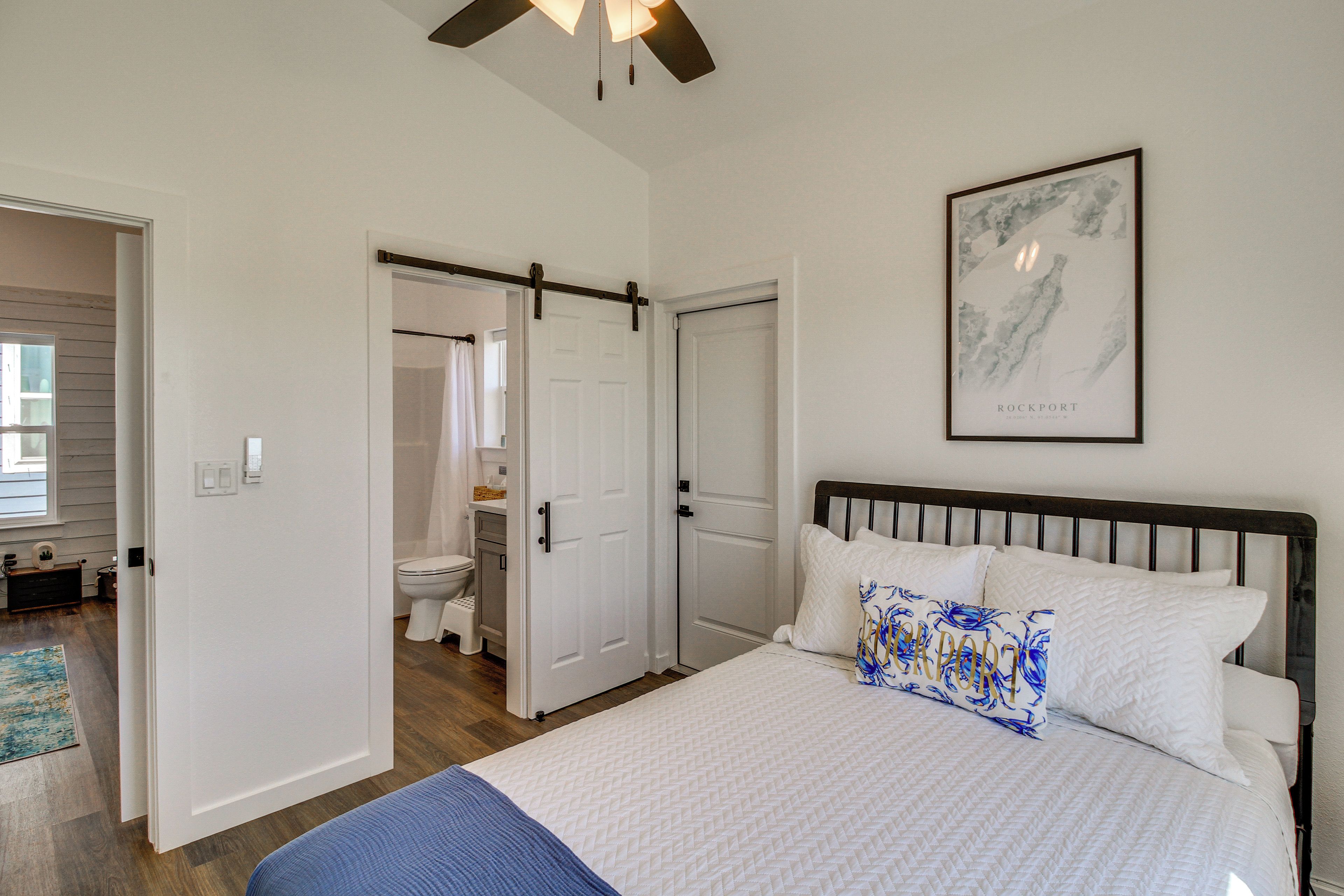 A bedroom with a bed, a bathroom with a toilet and shower, and a door leading to another room.