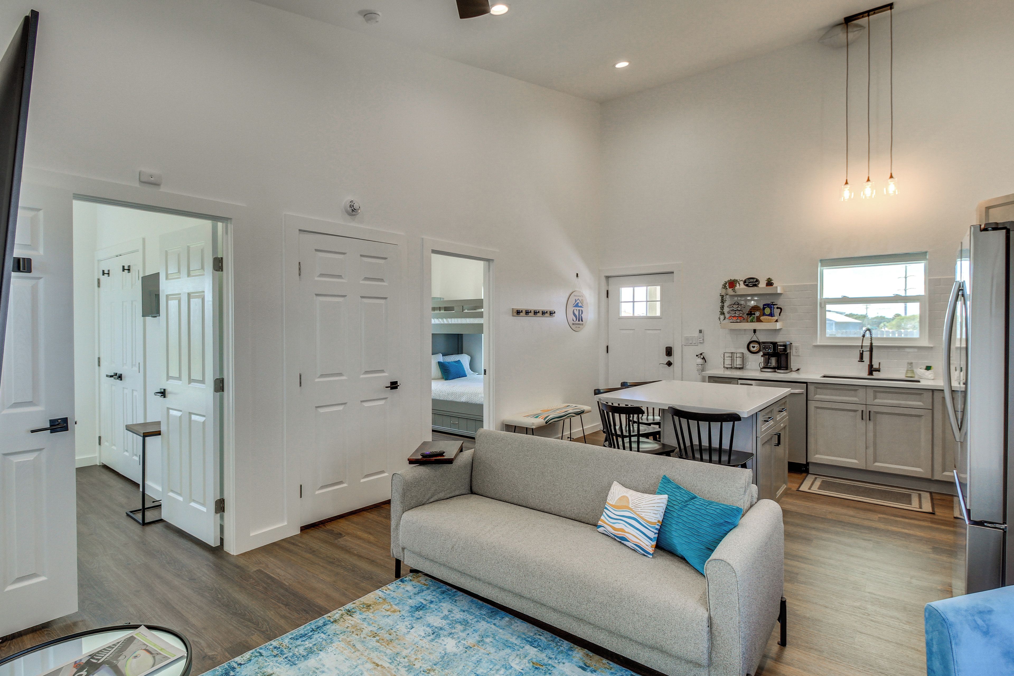 A modern interior with a living area, kitchenette, and a bedroom with a bed and a window.